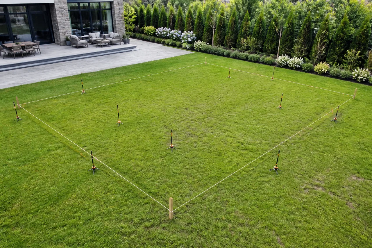 Vista aérea de un jardín con jalones y cuerdas marcando los límites de un terreno